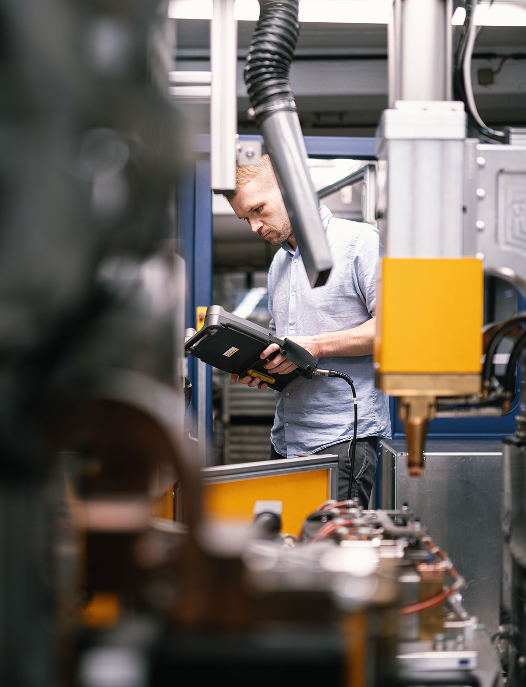 Mitarbeiter an Steuerungspanel einer hochautomatisierten Montageanlage nimmt Einstellungen und Anpassungen vor. Industrielle Fertigung und moderne Automatisierung